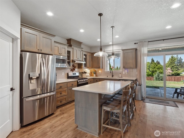 904 E Tanoak Ave, La Center, WA 98629 - kitchen featuring appliances with stainless steel finishes, light wood-style floors, backsplash, light countertops, and a sink