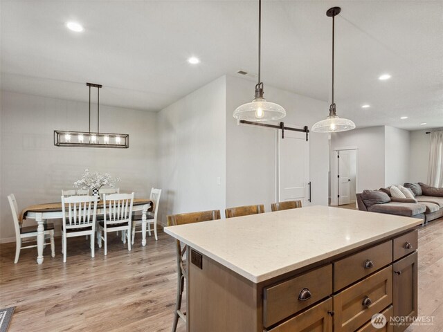 904 E Tanoak Ave, La Center, WA 98629 - kitchen with a barn door, light wood-style flooring, a breakfast bar area, recessed lighting, and pendant lighting