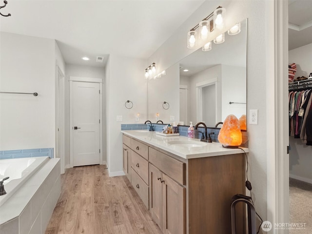904 E Tanoak Ave, La Center, WA 98629 - bathroom with double vanity, wood finished floors, a spacious closet, a relaxing tiled tub, and baseboards