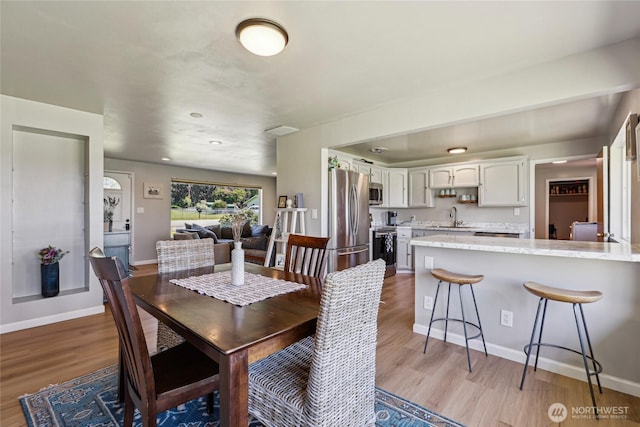dining space with wood finished floors, baseboards, and recessed lighting