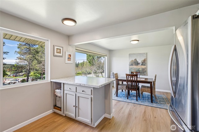 kitchen featuring freestanding refrigerator, light wood-style floors, light countertops, baseboards, and a peninsula