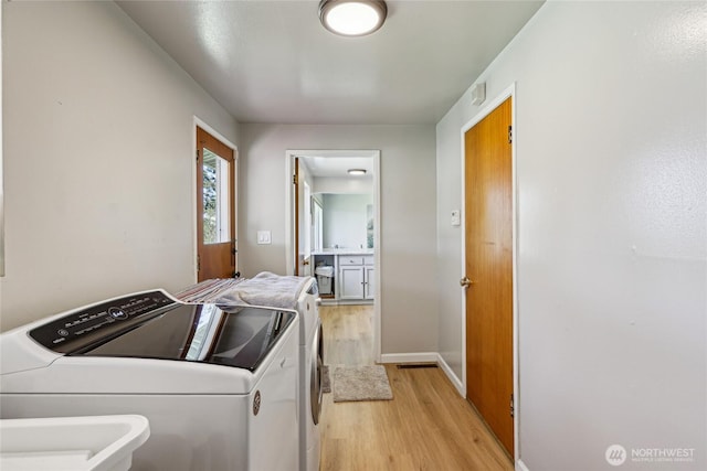 washroom with light wood-style floors, washing machine and dryer, and baseboards