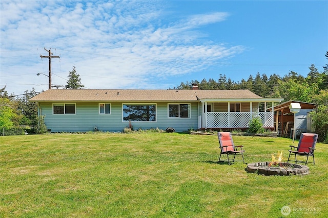 back of property with an outdoor fire pit, a lawn, a chimney, and an outdoor structure