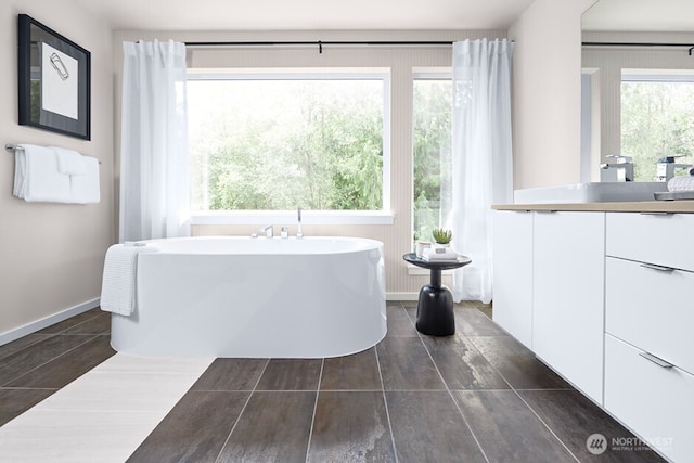 full bathroom featuring vanity, a freestanding tub, and baseboards