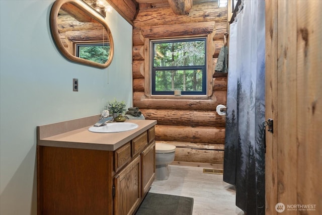 1321 E Smith Rd, Bellingham, WA 98226 - bathroom with log walls, vanity, toilet, and wood finished floors