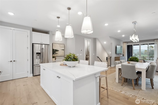 kitchen featuring a kitchen island, light wood-style floors, open floor plan, white cabinets, and stainless steel fridge with ice dispenser