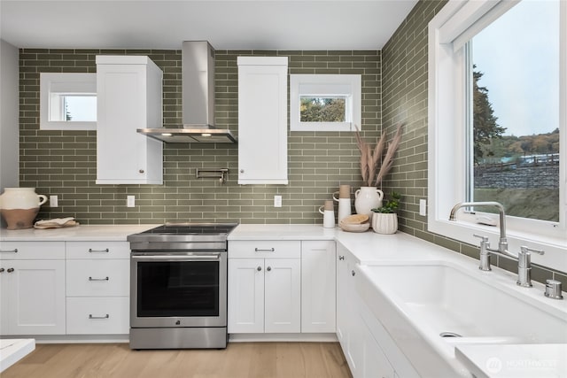 kitchen with plenty of natural light, a sink, stainless steel electric range, and wall chimney range hood