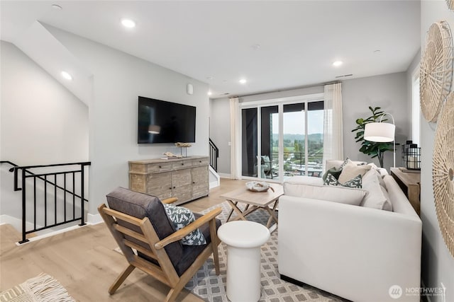 living room featuring recessed lighting, baseboards, wood finished floors, and stairway