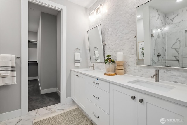 full bathroom featuring a walk in closet, a sink, a marble finish shower, marble finish floor, and baseboards