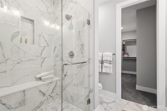 bathroom with toilet, a marble finish shower, marble finish floor, baseboards, and a spacious closet