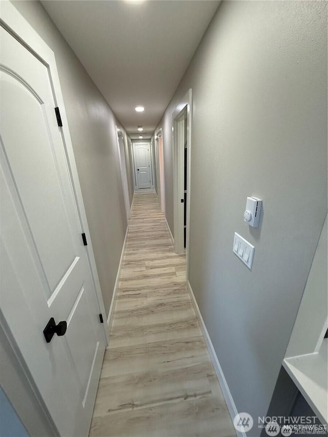 hall featuring light wood-style floors, recessed lighting, and baseboards