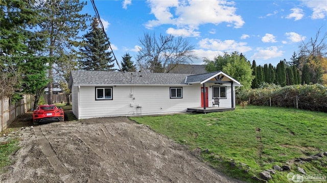 rear view of house with fence, a wooden deck, and a yard