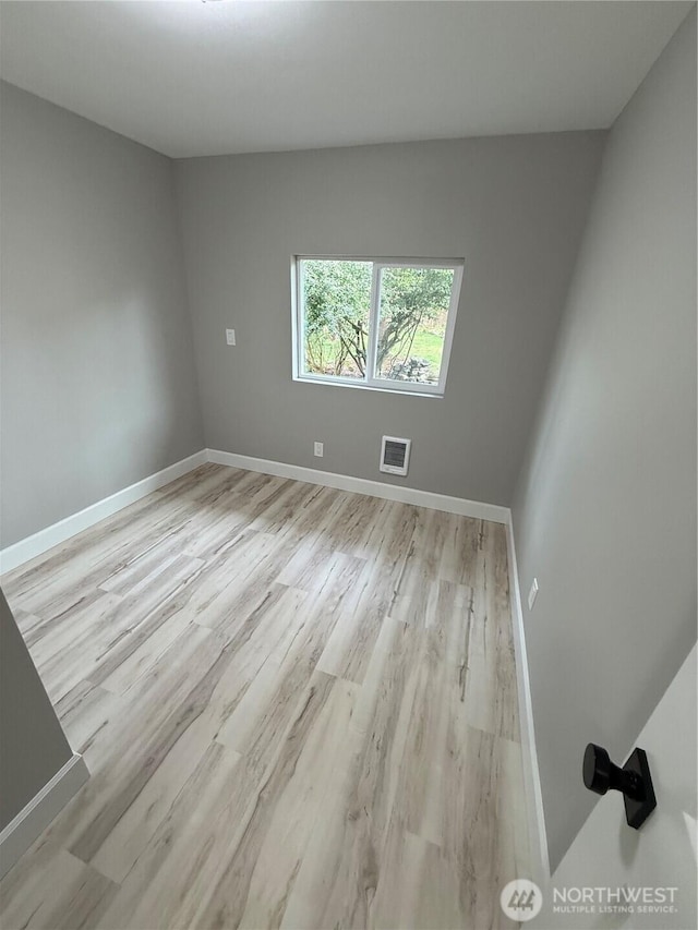 spare room featuring baseboards, visible vents, and light wood-type flooring