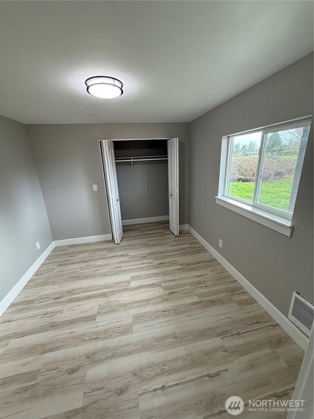 unfurnished bedroom featuring baseboards, visible vents, light wood-style flooring, and a closet