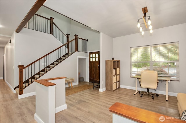office space featuring baseboards, light wood finished floors, and a notable chandelier