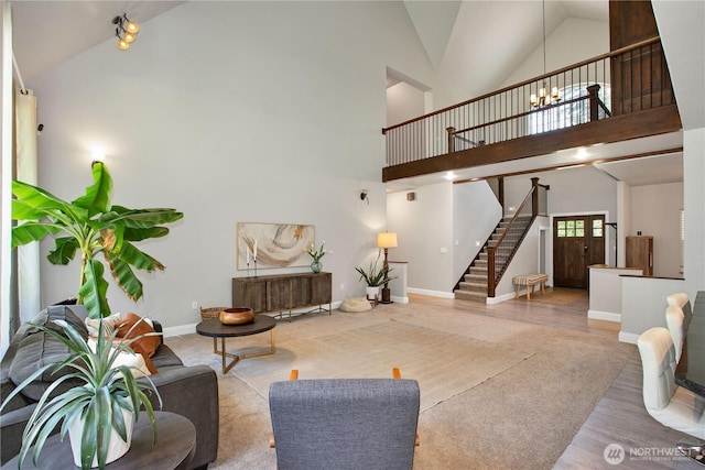 living area featuring wood finished floors, baseboards, high vaulted ceiling, an inviting chandelier, and stairs