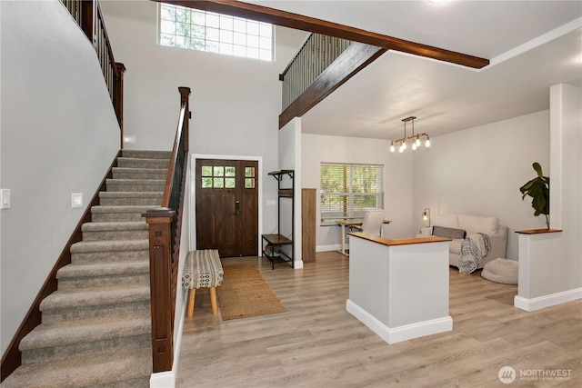 entrance foyer with light wood-style floors, baseboards, stairway, and an inviting chandelier