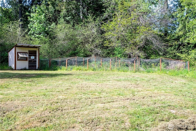 view of yard with an outdoor structure, fence, and a storage shed