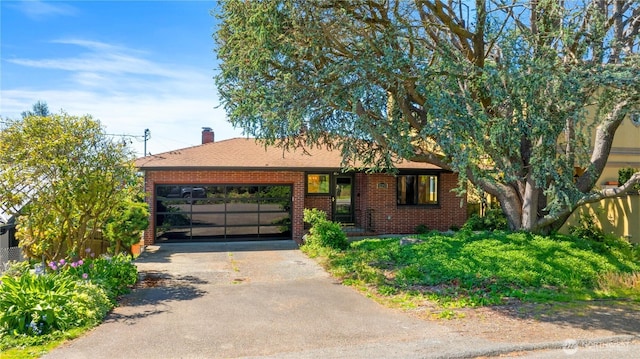 single story home with brick siding, an attached garage, aphalt driveway, and a chimney
