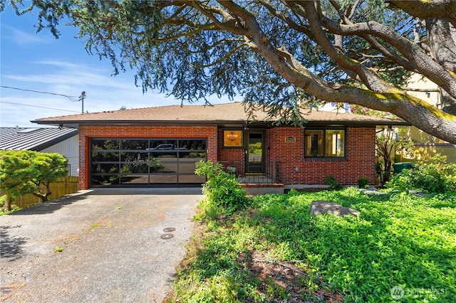 ranch-style home with brick siding, an attached garage, and aphalt driveway