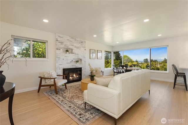 living room with recessed lighting, baseboards, a tile fireplace, and light wood-type flooring