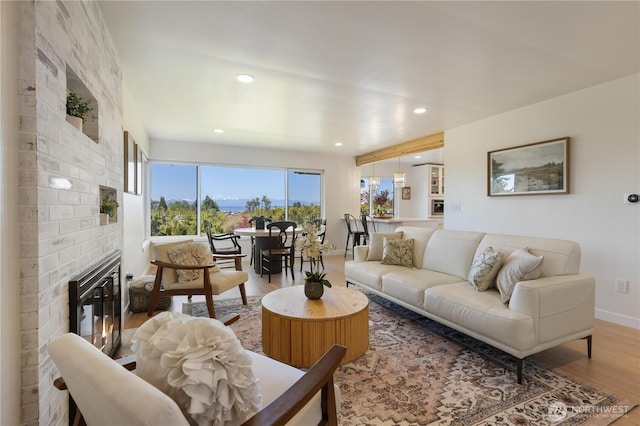 living area featuring baseboards, recessed lighting, a brick fireplace, and wood finished floors