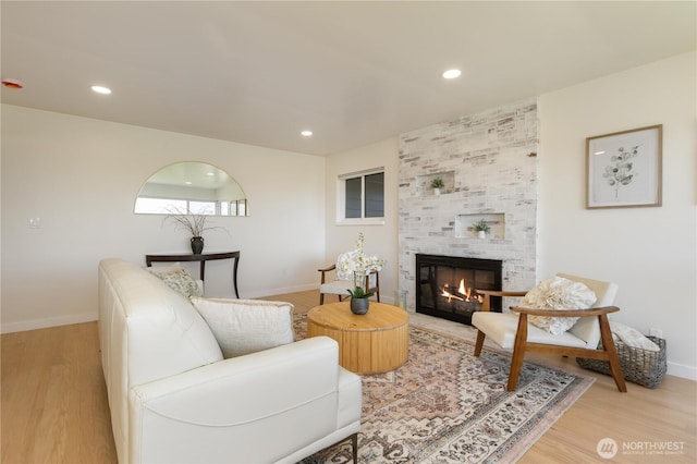 living area featuring baseboards, light wood-style flooring, and a fireplace
