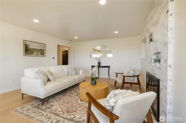 living room featuring baseboards, a fireplace, recessed lighting, and wood finished floors