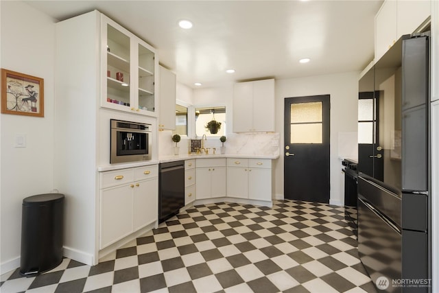 kitchen with a sink, light countertops, light floors, and black appliances