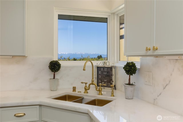 kitchen featuring light countertops, white cabinetry, a sink, and backsplash