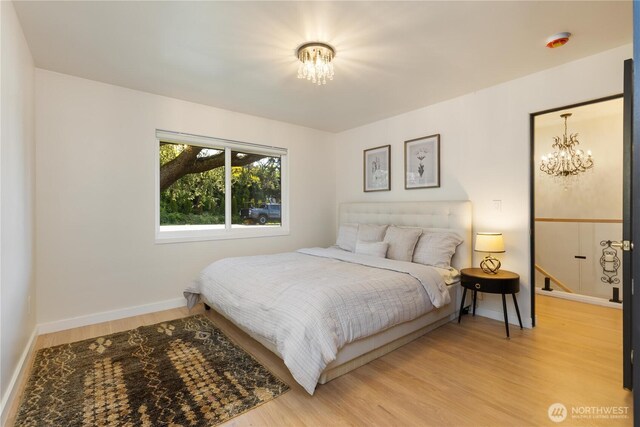 bedroom featuring baseboards, light wood-style flooring, and a notable chandelier