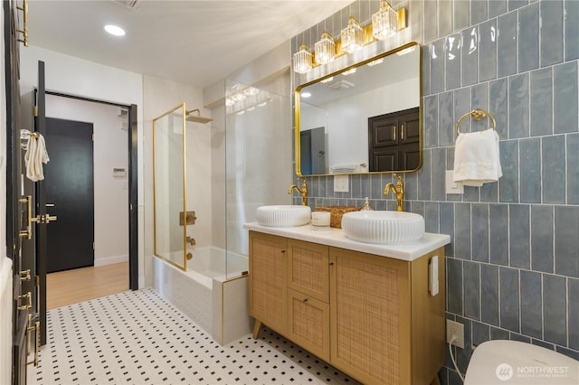 bathroom featuring a sink, enclosed tub / shower combo, and tile walls
