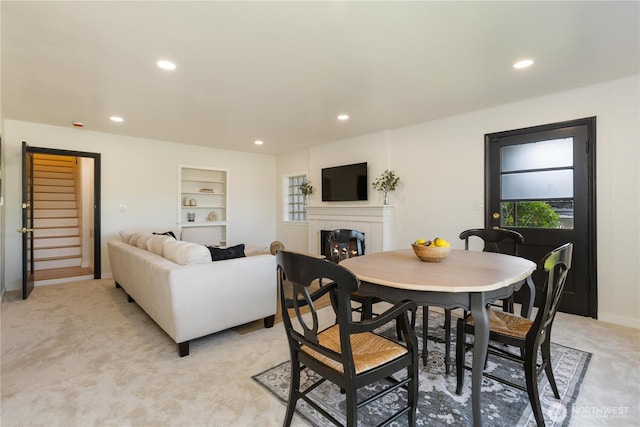 dining area featuring recessed lighting, light colored carpet, and a tile fireplace