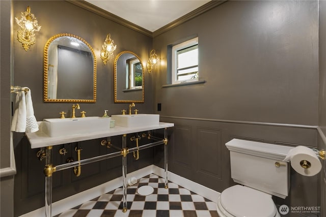 bathroom with a sink, tile patterned floors, toilet, ornamental molding, and a decorative wall