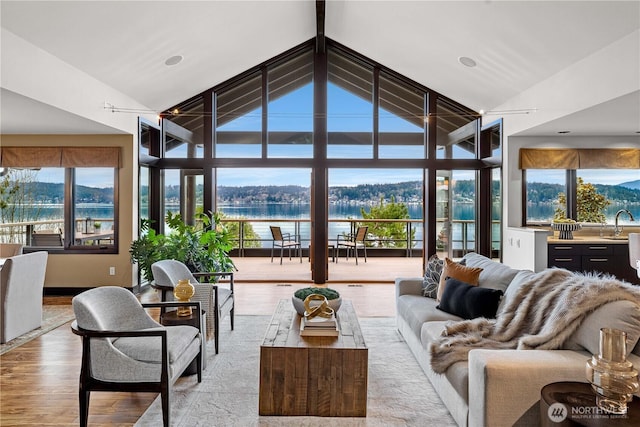 living area featuring a water view, high vaulted ceiling, and wood finished floors