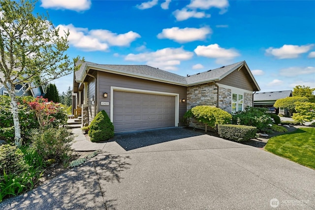 view of front of house featuring an attached garage, driveway, and stone siding