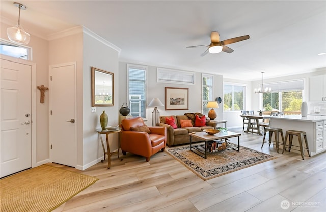 living room with a wealth of natural light, light wood-type flooring, and ceiling fan with notable chandelier