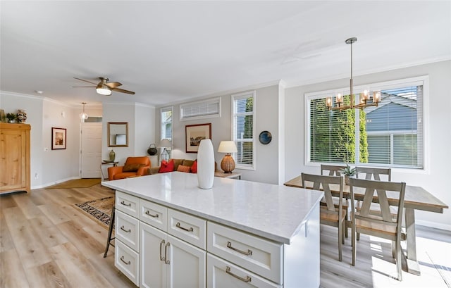 kitchen featuring white cabinetry, light wood finished floors, crown molding, and ceiling fan with notable chandelier