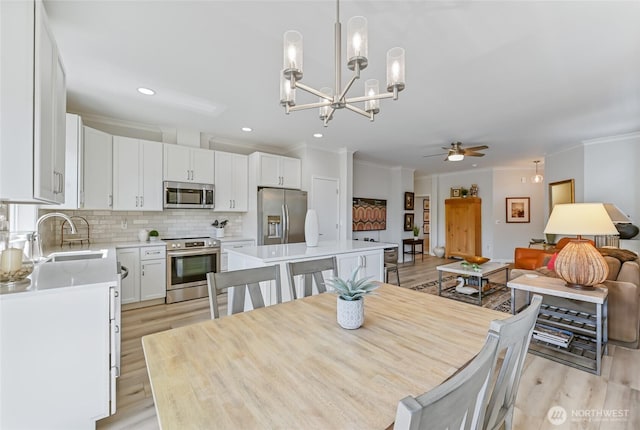 dining room featuring light wood finished floors, crown molding, ceiling fan with notable chandelier, and recessed lighting