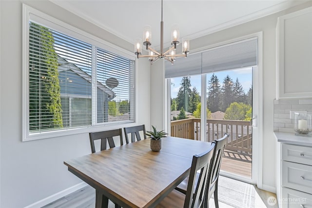 dining room featuring a chandelier, ornamental molding, baseboards, and light wood finished floors