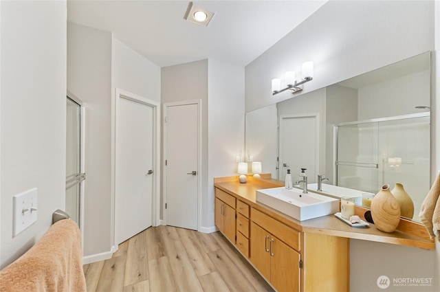 bathroom with vanity, baseboards, a shower stall, and wood finished floors