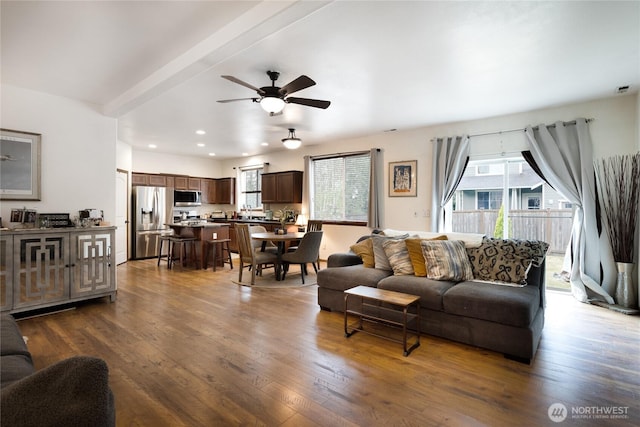 living room featuring dark wood finished floors, a ceiling fan, and a healthy amount of sunlight