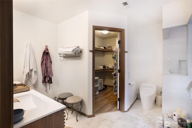 full bath featuring a walk in closet, toilet, baseboards, and visible vents