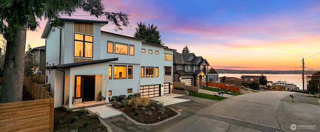 modern home with fence, board and batten siding, an attached garage, and concrete driveway