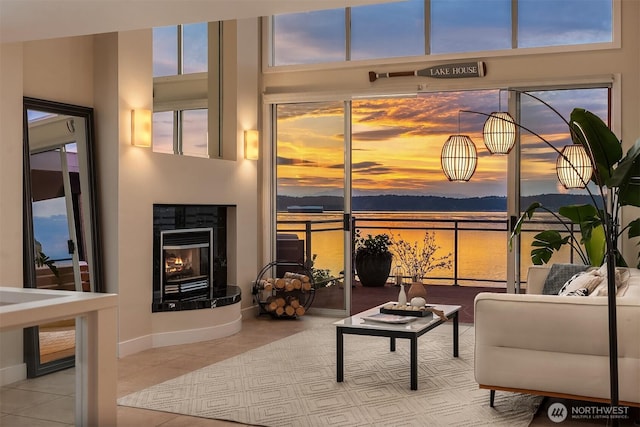 living room with tile patterned floors, a glass covered fireplace, and baseboards