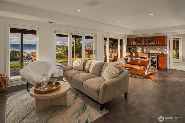 living area with beverage cooler, a bar, recessed lighting, and finished concrete flooring