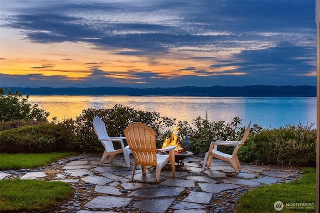 patio terrace at dusk featuring a water view