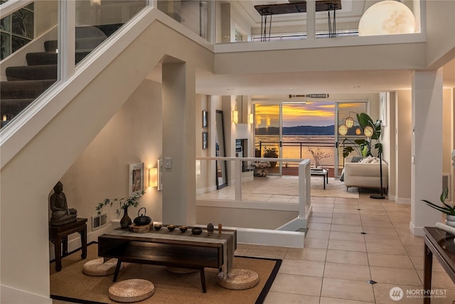 entrance foyer with tile patterned floors, a high ceiling, baseboards, and stairway