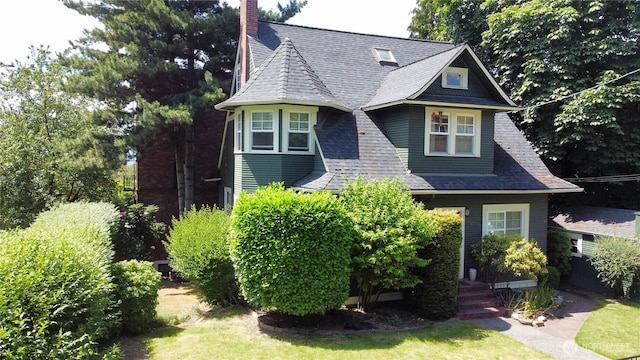 victorian house featuring roof with shingles and a chimney