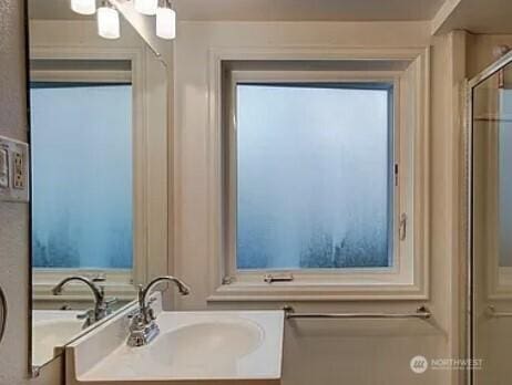 full bathroom with an enclosed shower and a sink